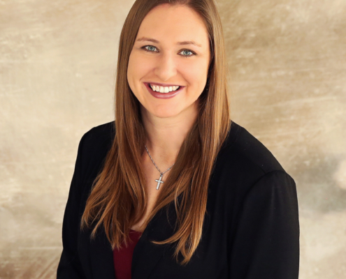 Renae Keller wears a black blazer in front of a tan background.