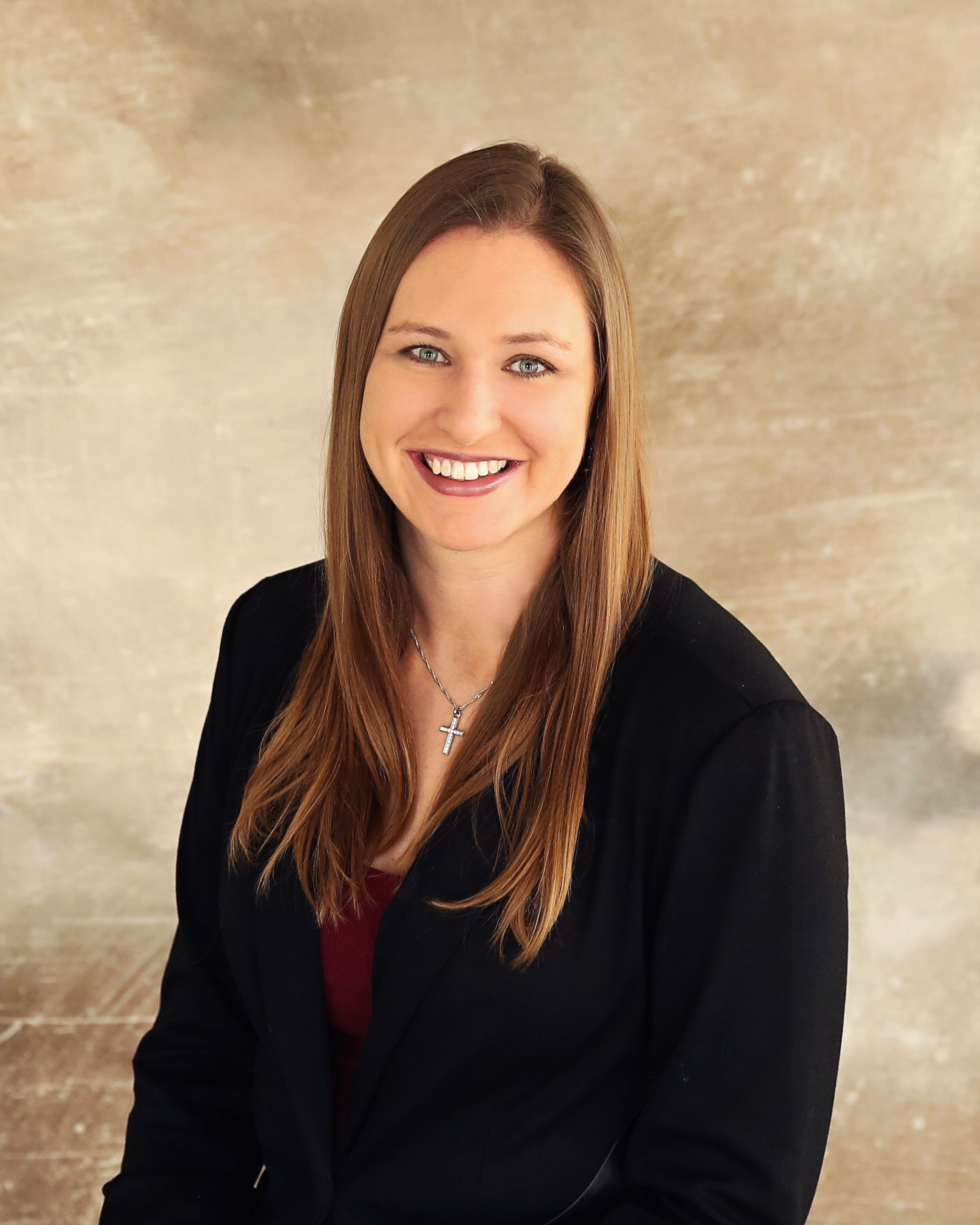 Renae Keller wears a black blazer in front of a tan background.